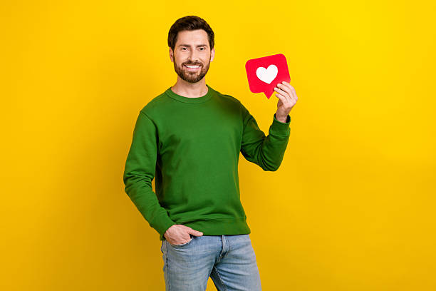 istock Photo of optimistic man dressed pullover hold red paper card facebook instagram like reaction isolated on yellow color background 2213909135