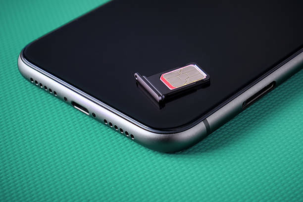 istock Sim card lying on a dark smartphone. Replacing SIM cards for a smartphone. 2213923507