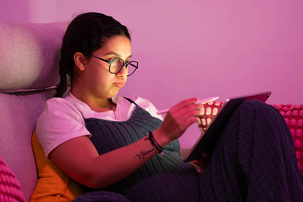 istock Pregnant woman relaxing on sofa using digital tablet with pen 2213923827