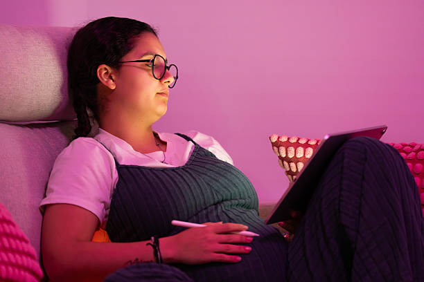 istock Pregnant woman relaxing on sofa using digital tablet and stylus 2213923905