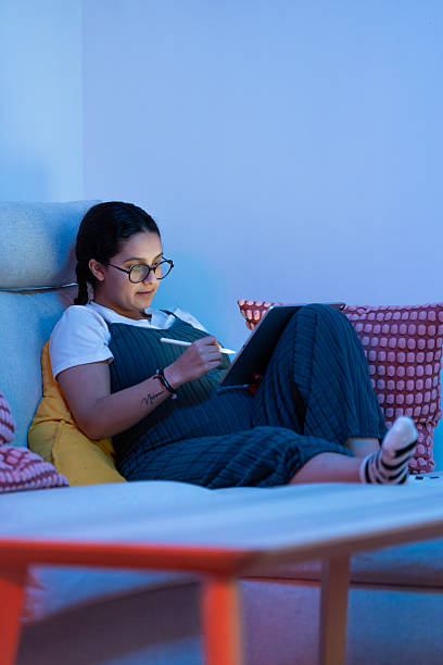 istock Pregnant woman relaxing on sofa and drawing on tablet 2213924006