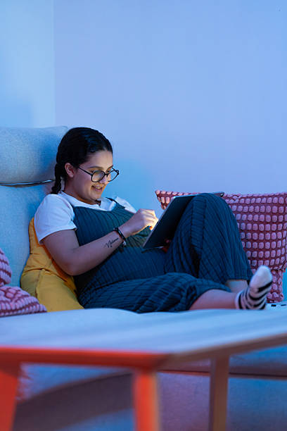 istock Pregnant woman relaxing on sofa using digital tablet at night 2213924024