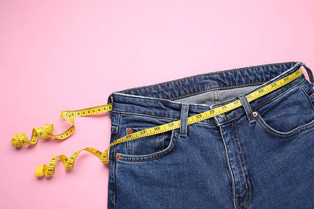 istock Jeans and measuring tape on pink background, top view 2213925324