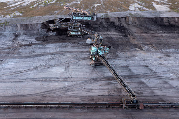 Aerial view of a lignite surface mine with a giant bucket-crawler excavator and conveyor belt.