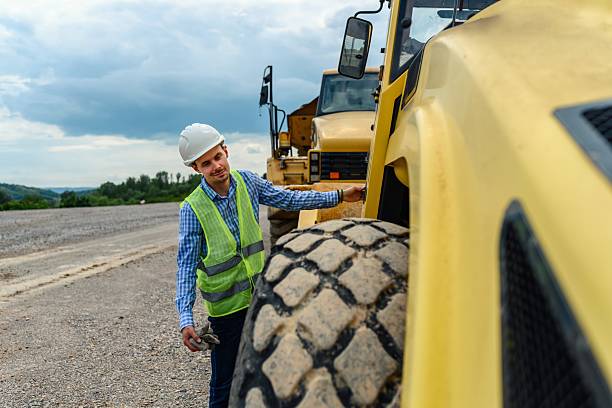 istock Construction worker inspecting heavy machinery on a road repair site 2213925466