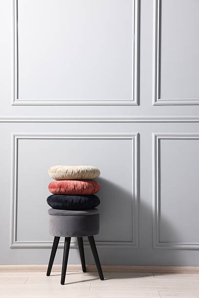 istock Stylish stool and cushions near light grey wall indoors, space for text 2213925886