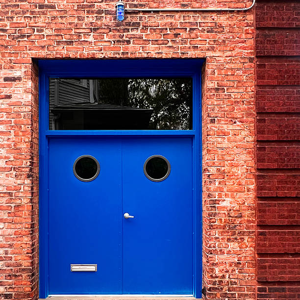 Weathered blue wooden double entrance doors with transom windows.