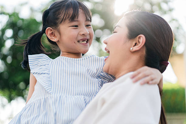 istock Mother Lifting Smiling Daughter Outdoors in Sunshine 2213929897