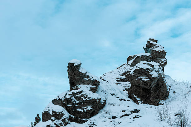 A snow-covered mountain with a rocky terrain. The sky above is a deep blue color, and there are no clouds visible. The scene is calm and tranquil