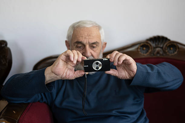 istock Senior man holding a vintage camera at home 2213935321