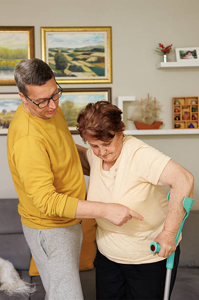 istock Son Helping Mother with Limited Mobility Stand Up Safely 2213939070