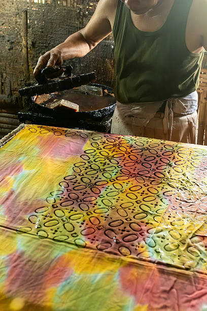 istock Artisan applying hot wax to batik fabric with traditional tool 2213948865