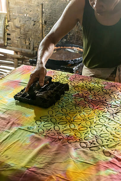 istock Artisan applying batik stamp on colorful fabric 2213953457