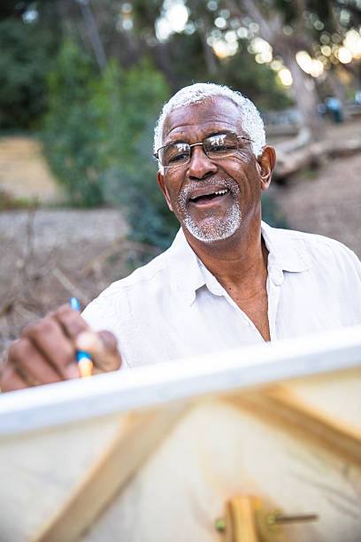 Senior black man painting in nature