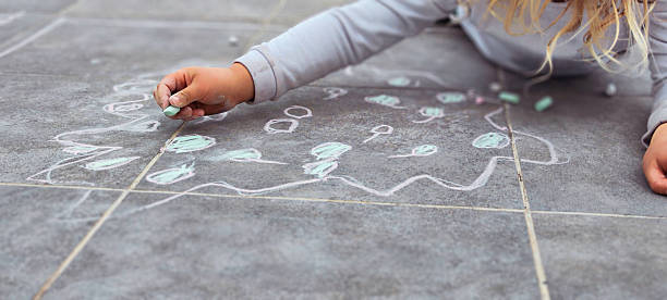Little girl drawing with chalk on the ground, expressing her creativity