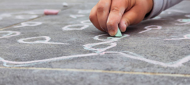 istock Kid drawing hopscotch with chalk on the pavement 2213955179
