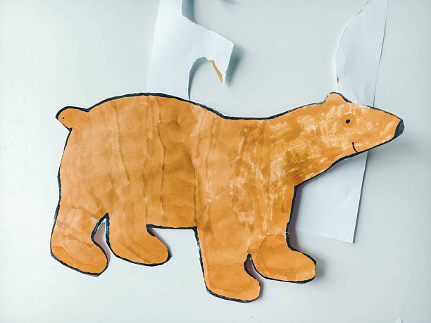Bear figure cut out with scissors on white table. Children's creativity.