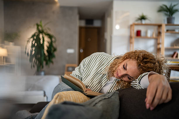 istock Woman relaxing on sofa reading a book at home 2213957533