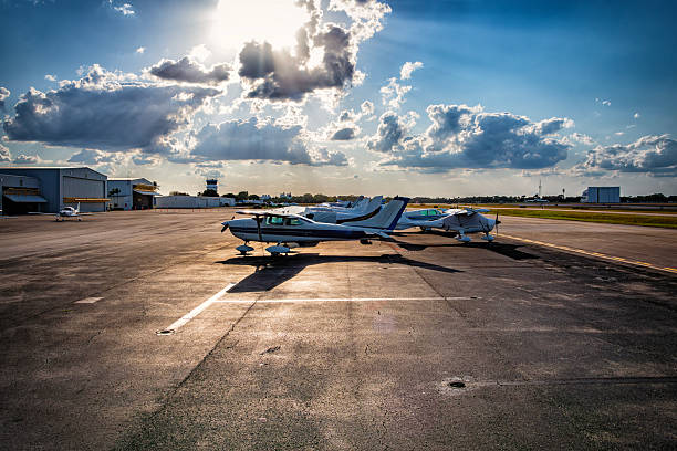 The tails of private business jets are silhouetted by the rising sun on a clear morning.