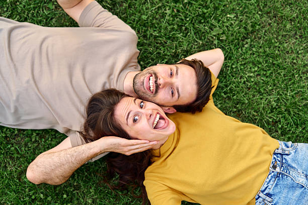 istock Young couple lying on grass making funny faces 2213959741