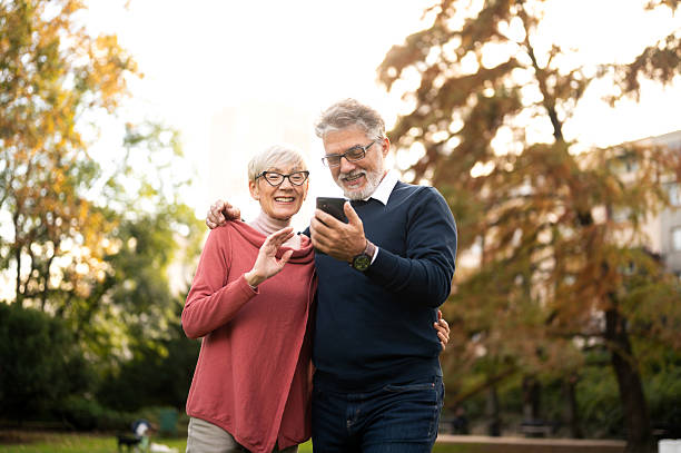 istock Romantic senior couple walking and using smart phone in public park 2213965644