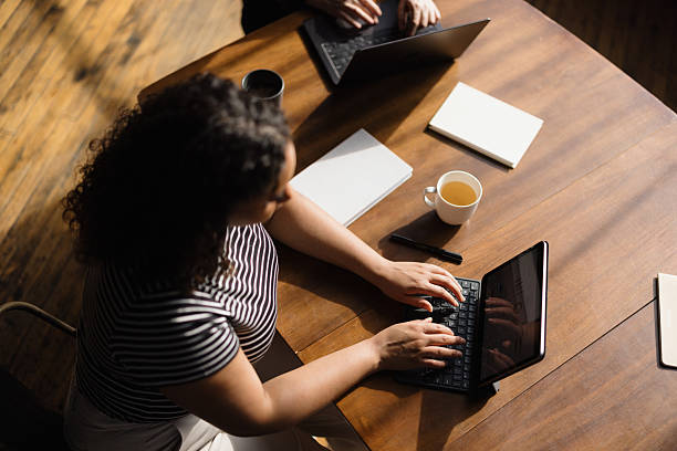 istock Coworkers typing on laptops and tablets at wooden table 2213966200