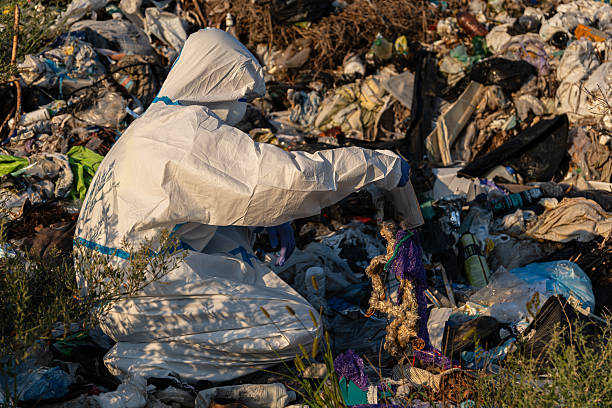 istock An environmental worker in protective gear is sorting through trash in a landfill during sunset, aiming to clean up plastic waste 2213968184