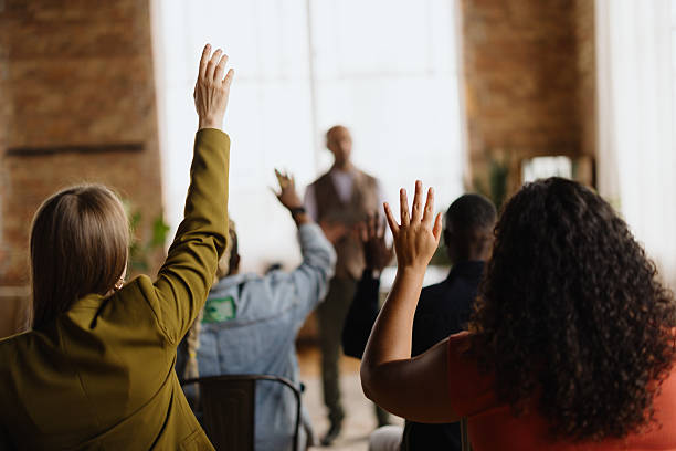 istock Audience raising hands to ask questions during a business conference 2213968632