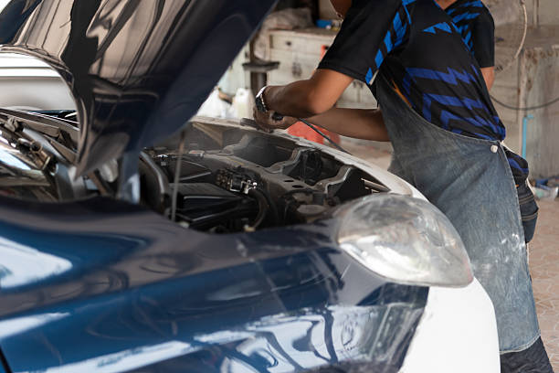 Middle-aged male mechanic repairing car on the road