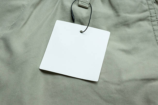 istock Blank white clothes tag label on gray fabric texture background 2213972411