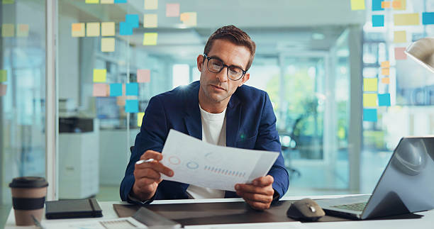 istock Businessman, finance or documents with statistics for analytics or company performance at office. Man, employee or financial analyst with paperwork or chart for business growth or report at workplace 2213978886