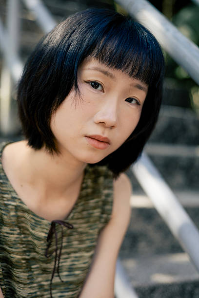 istock Young Asian Woman with Natural Expression Sitting on Outdoor Steps 2213979088