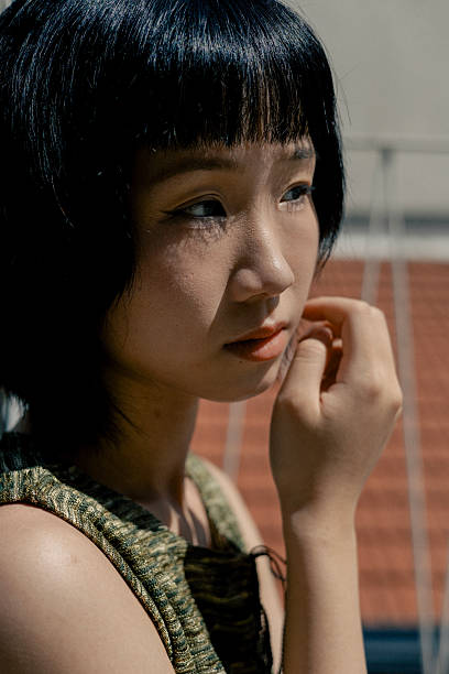 istock Young Asian Chinese Woman Looking Sideways in Harsh Daylight on Rooftop 2213979170
