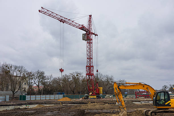 istock A large red crane stands at a construction site with heavy machinery working amid overcast weather, indicating ongoing building activity 2213980644