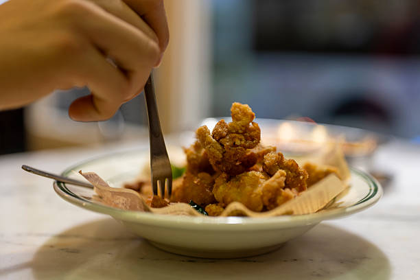 A person crosses the crispy fried chicken on a plate