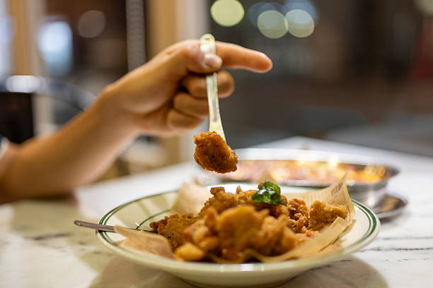 A person crosses the crispy fried chicken on a plate