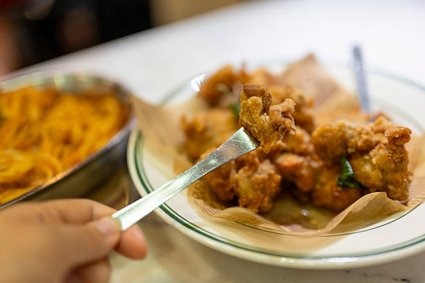 A person crosses the crispy fried chicken on a plate
