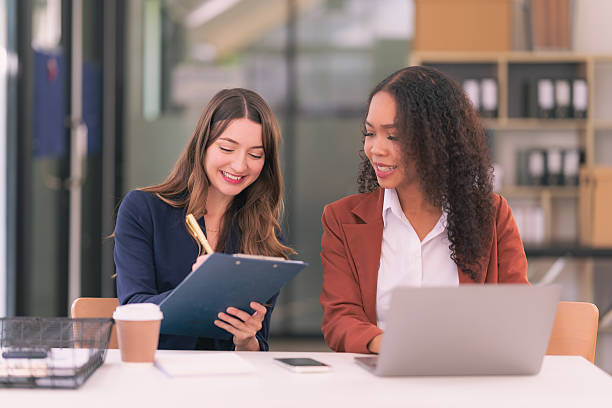 istock Two businesswomen in suits working and brainstorming together using computer technology documents financial graphs for analysis in modern office 2213987574