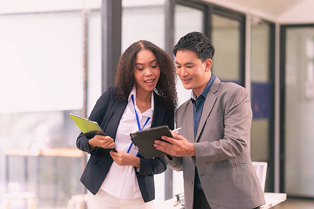 istock Two businessmen and women in suits working together and brainstorming using computer technology creating financial charts for analysis in modern office. 2213987642
