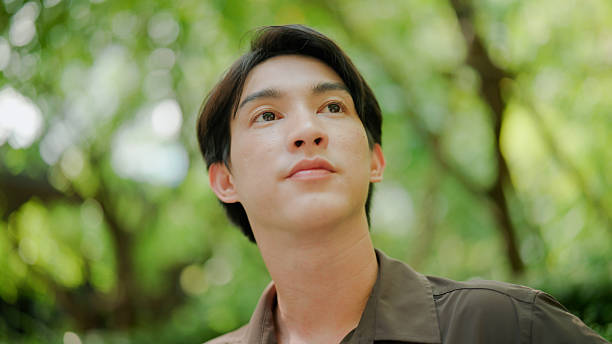 istock Young Asian man breathing fresh air while relaxing on a park bench. 2213991425