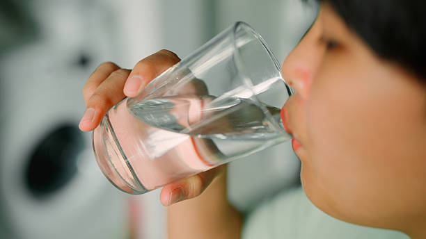 istock Asian woman drinking water from glass 2213997104