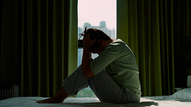 istock Asian woman sitting on bed and looking through window 2213997117