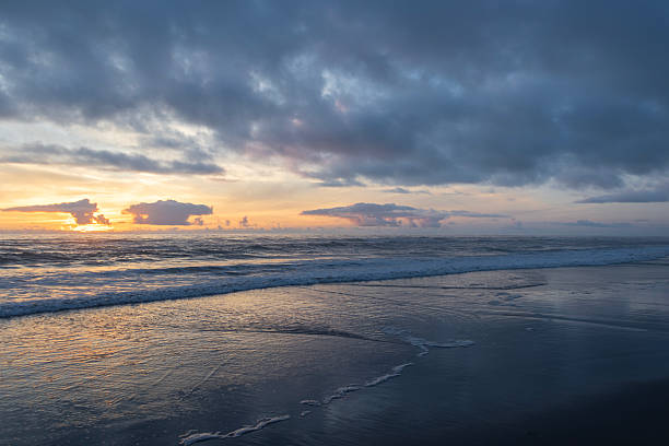 istock Sunset over the ocean with waves gently lapping at the sandy beach in a quiet coastal area 2214002091