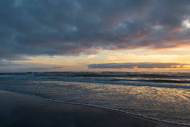 istock Sunset over the ocean with gentle waves and cloudy sky at a serene beach location 2214002092