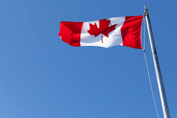 istock Canadian flag waving against clear blue sky 2214002369