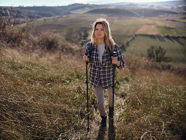 istock Smiling female backpacker moving up the hill in autumn day. 2214002940