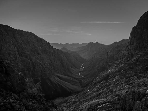 A grayscale of a winding river through a rugged valley