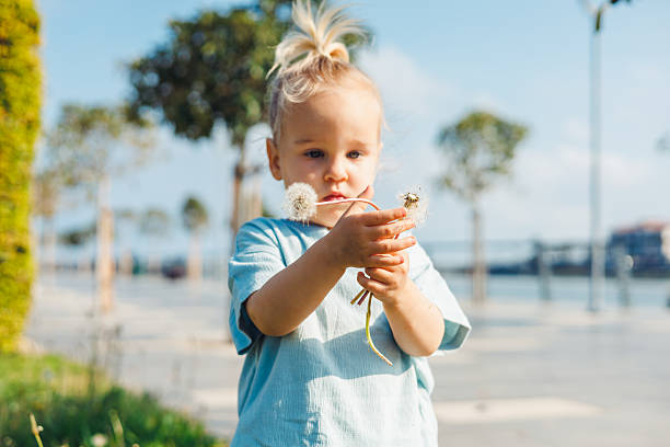 istock Child enjoys a sunny day outdoors while holding a delicate flower in a scenic park 2214003413