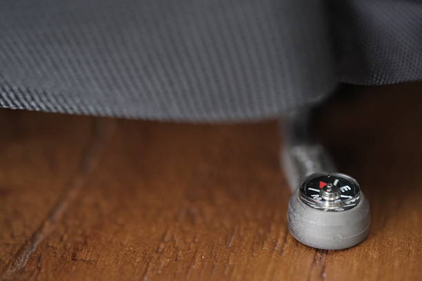 Macro shot of a tiny directional compass embedded in a paracord or zipper pull, symbolizing travel, survival, and exploration