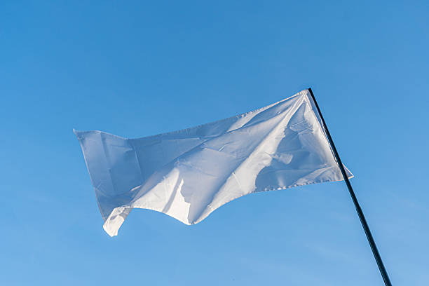 istock A white flag flutters on a building rooftop against a bright, cloudy sky during daylight a 2214009216